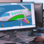 Computer monitor displaying a 3D engineering assembly in CAD software with an AI assistant interface for design review and model analysis